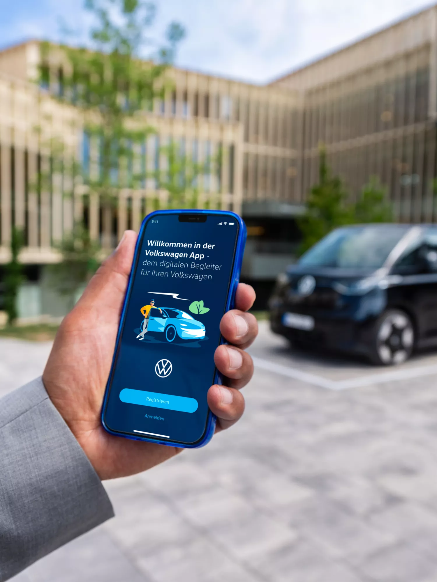 Mann meldet sich bei der Volkswagen App an, schwarzer ID. Buzz im Hintergrund