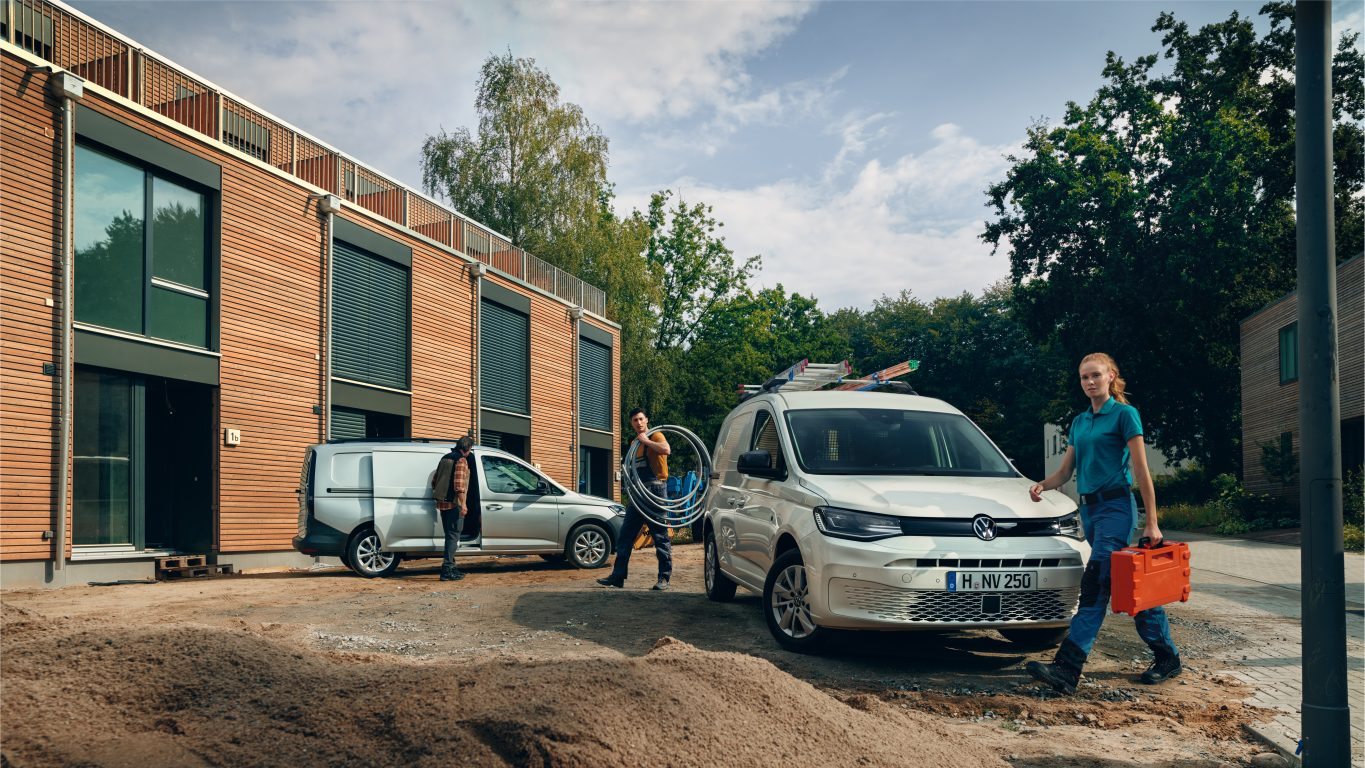 Zwei Caddy stehen auf einer Baustelle, 3 Handwerker daneben