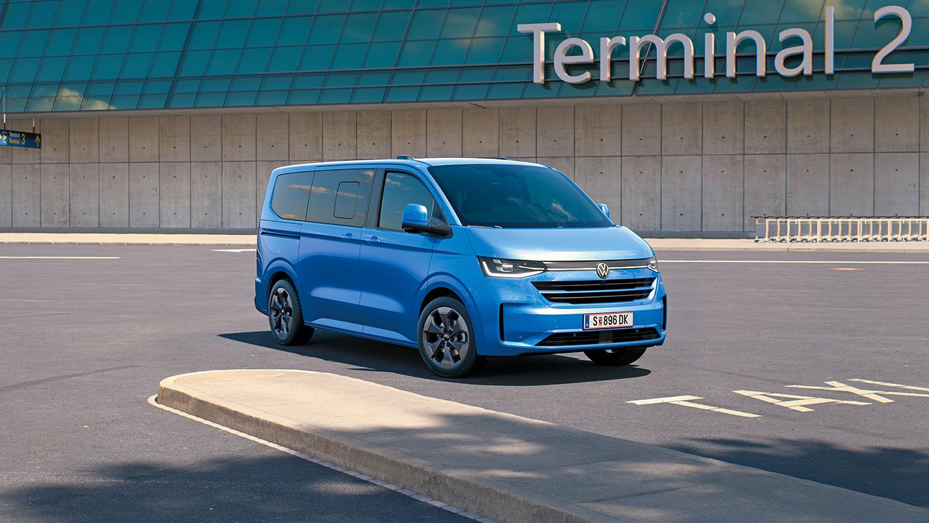 Ein VW Caravelle steht vor dem Terminal 2 auf einem Flughafenparkplatz