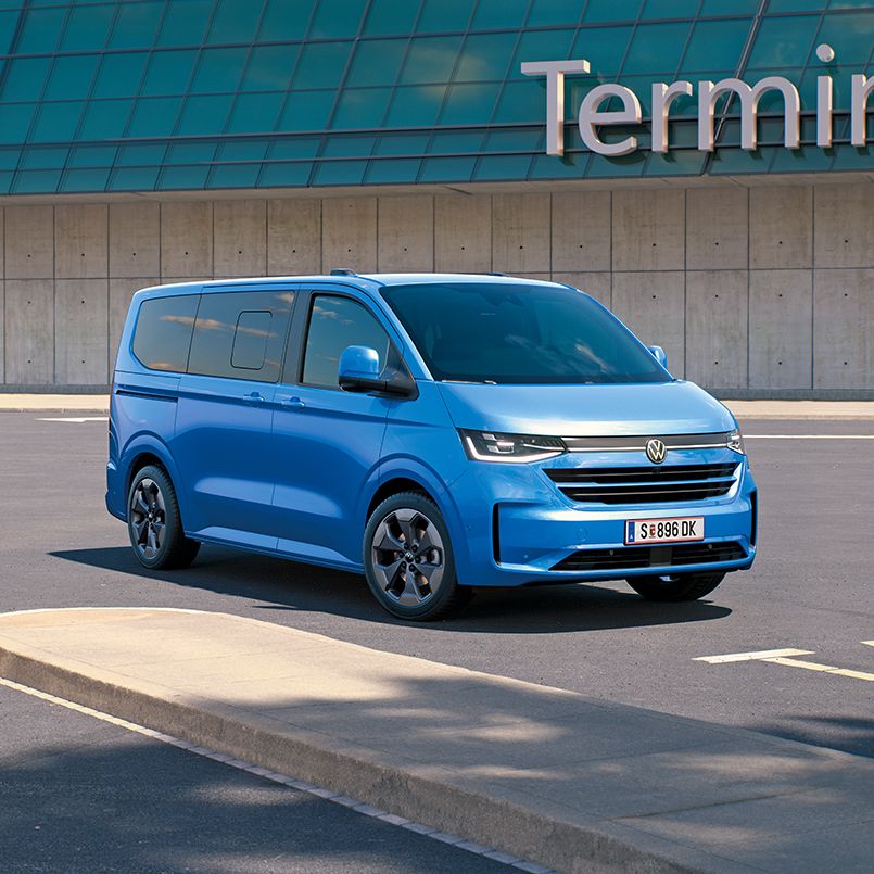 Ein VW Caravelle steht vor dem Terminal 2 auf einem Flughafenparkplatz