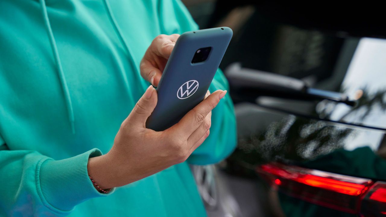 Eine Frau tippt in ihr Smartphone. Auf der blauen Schutzhülle ist das Volkswagen Logo abgebildet.