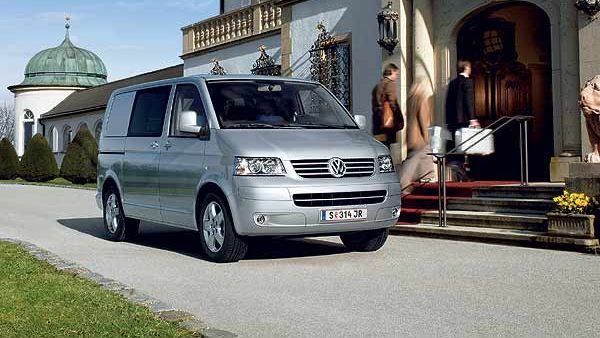 VW Bulli T5 in Silber vor einem Hotel