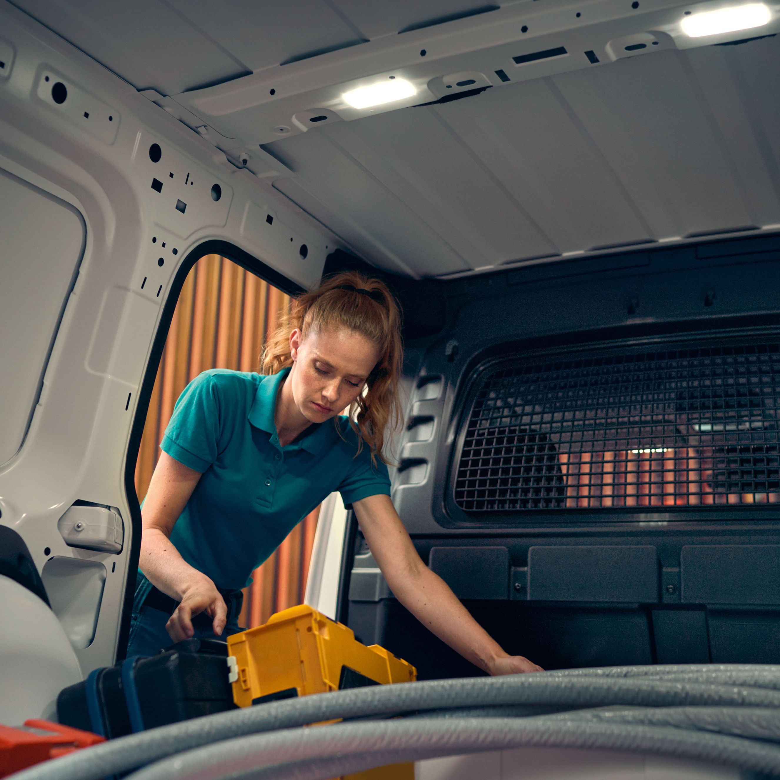 Eine Frau beim Beladen eines weißen VW Caddy Cargo.