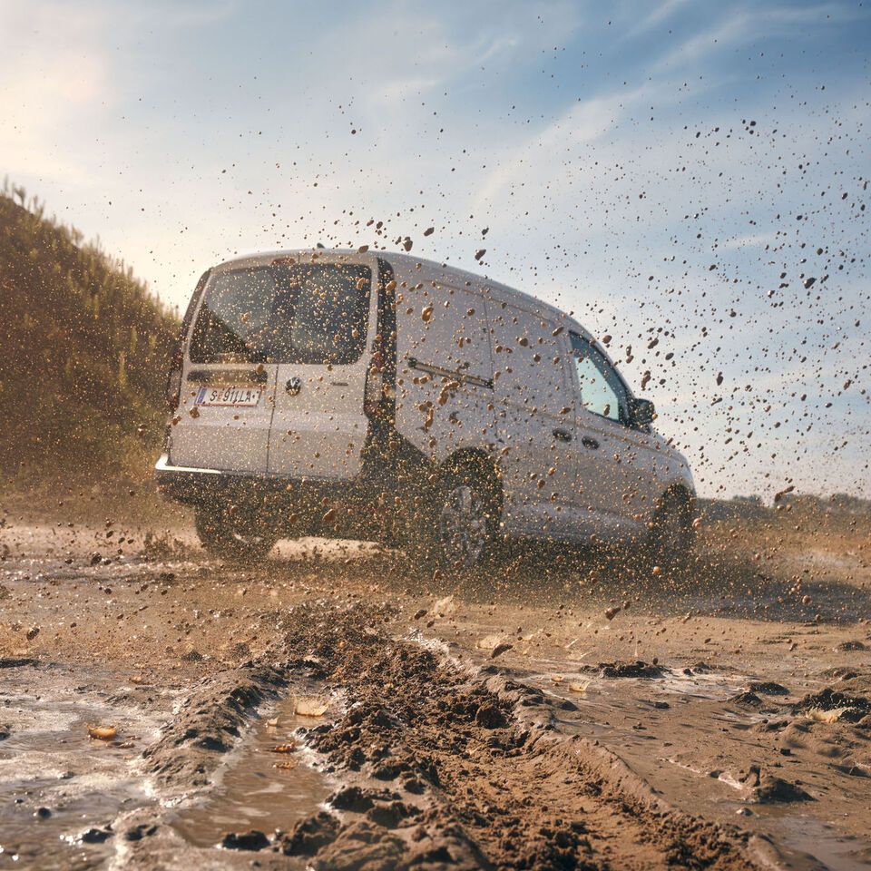 VW Caddy in weiß, fährt durch matschige Landschaft