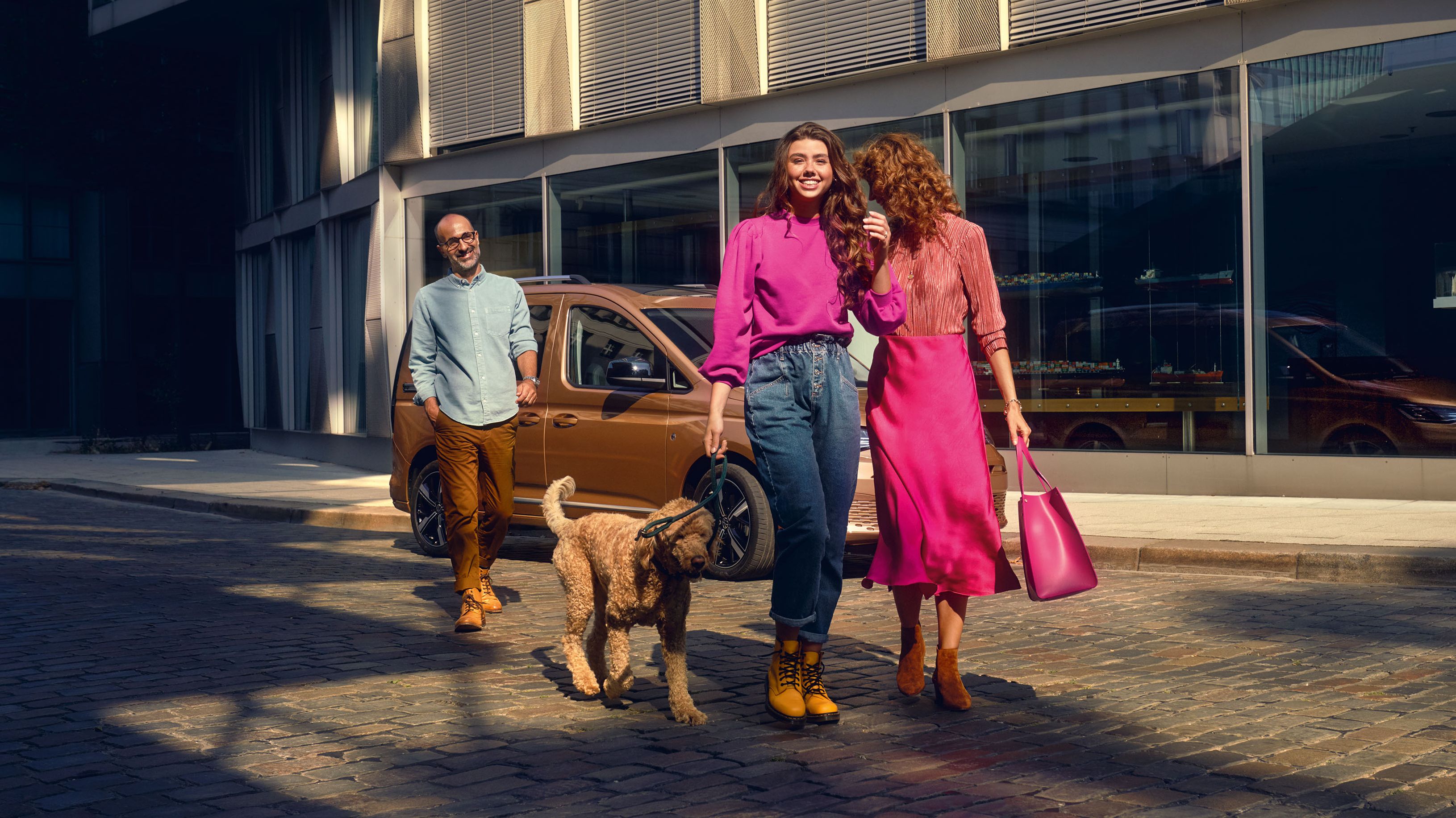 Eine Familie mit Hund bewegt sich von ihrem VW Caddy fort