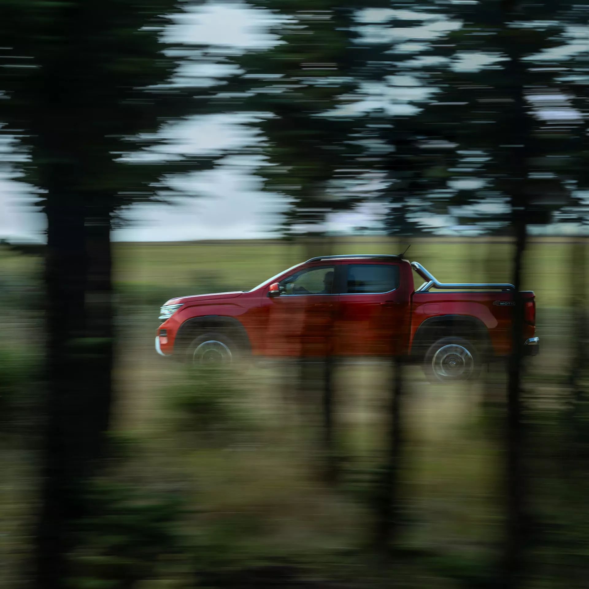 Seitenansicht VW Amarok, fährt durch Wald bei Nacht