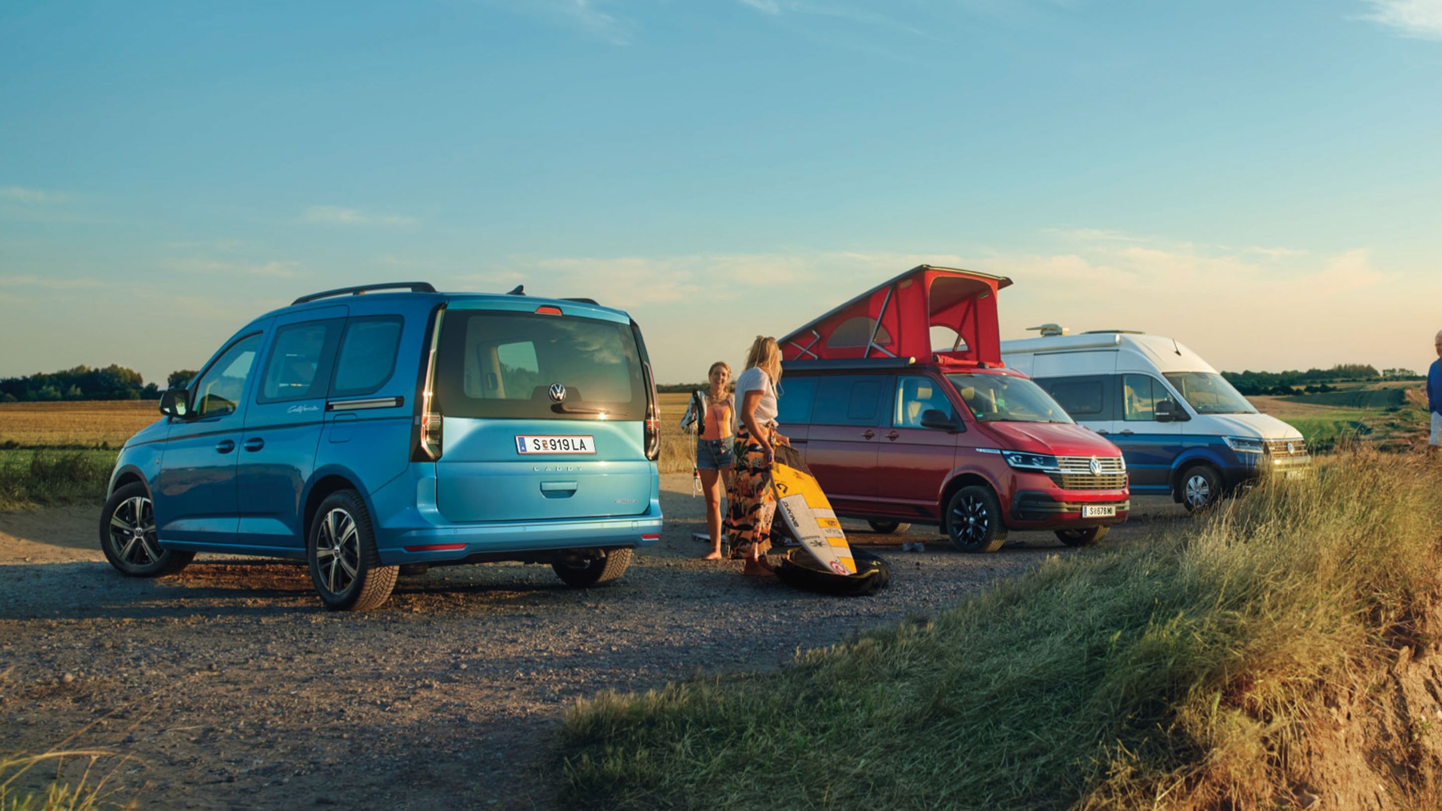 VW Caddy blau, Grand California und California 6.1 stehen nebeneinander am Strand