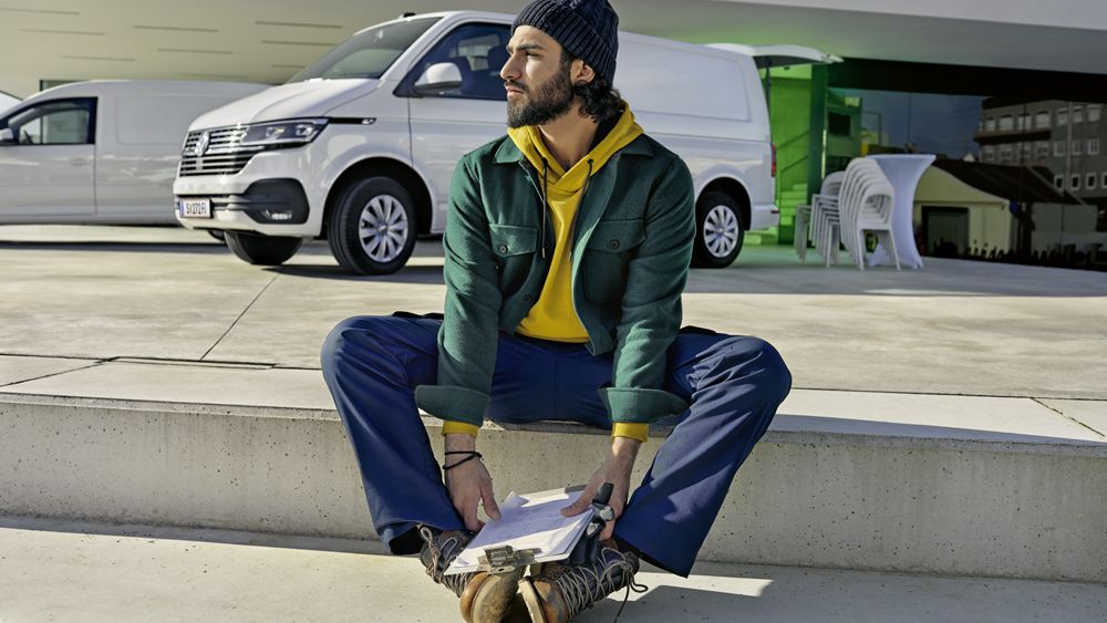 Mann sitzt vor einem VW Transporter im Hintergrund