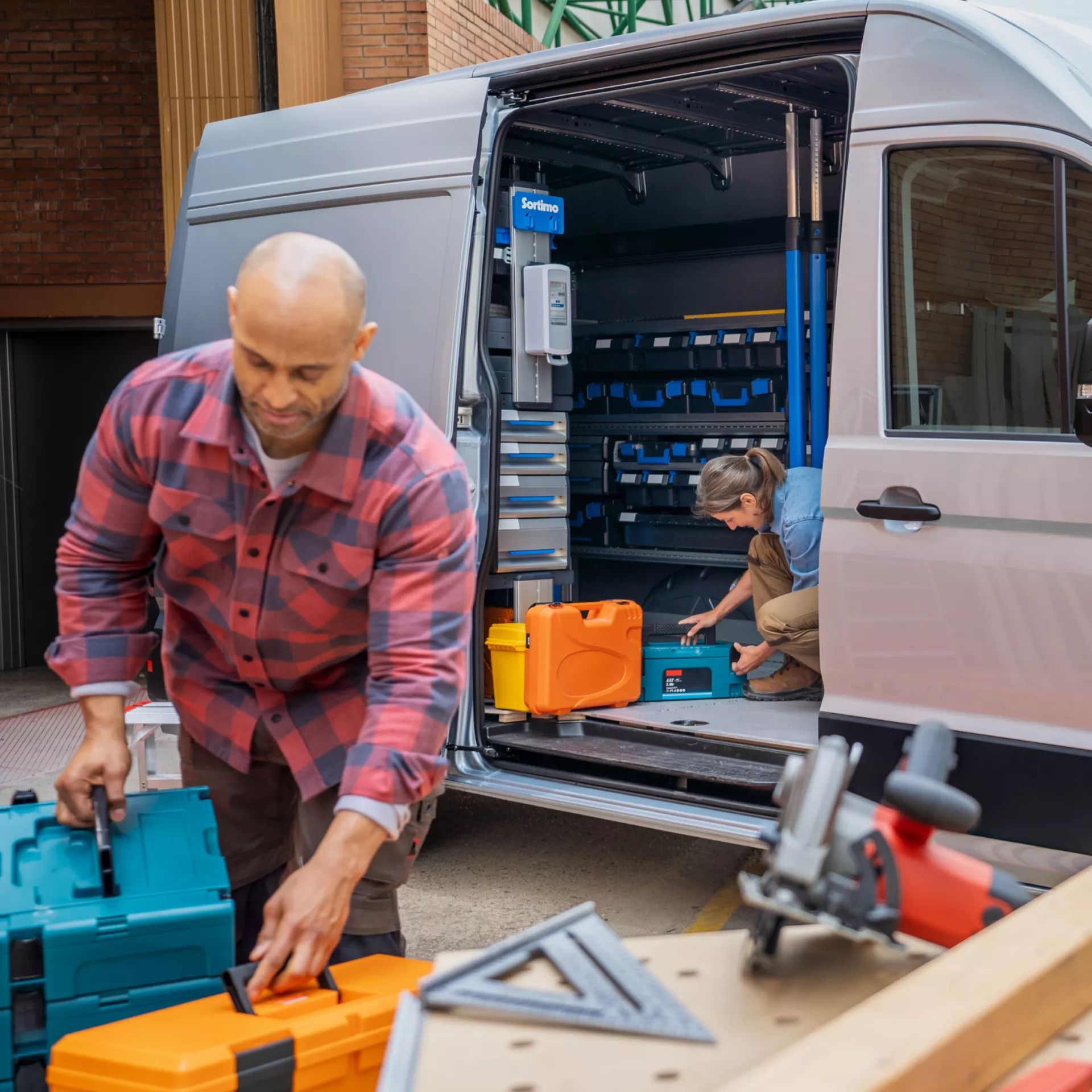 Zwei Handwerker nutzen einen VW Crafter als Arbeitsfahrzeug, geöffnete Schiebetür