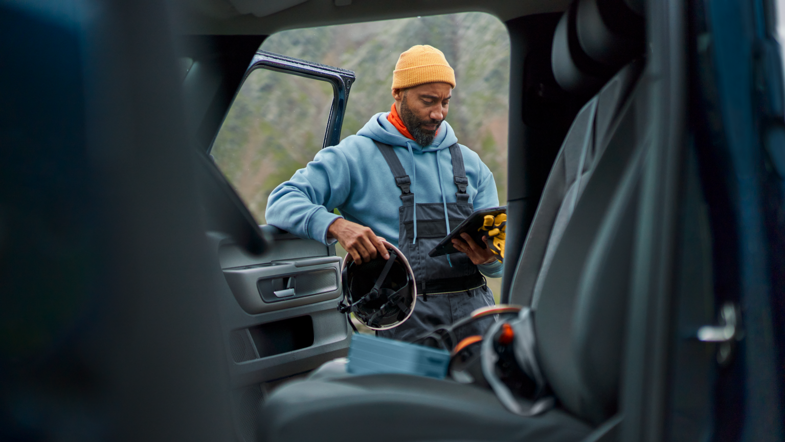 Blick aus einem Volkswagen Nutzfahrzeug-ein Mann mit Tablet lehnt an der geöffneten Türe