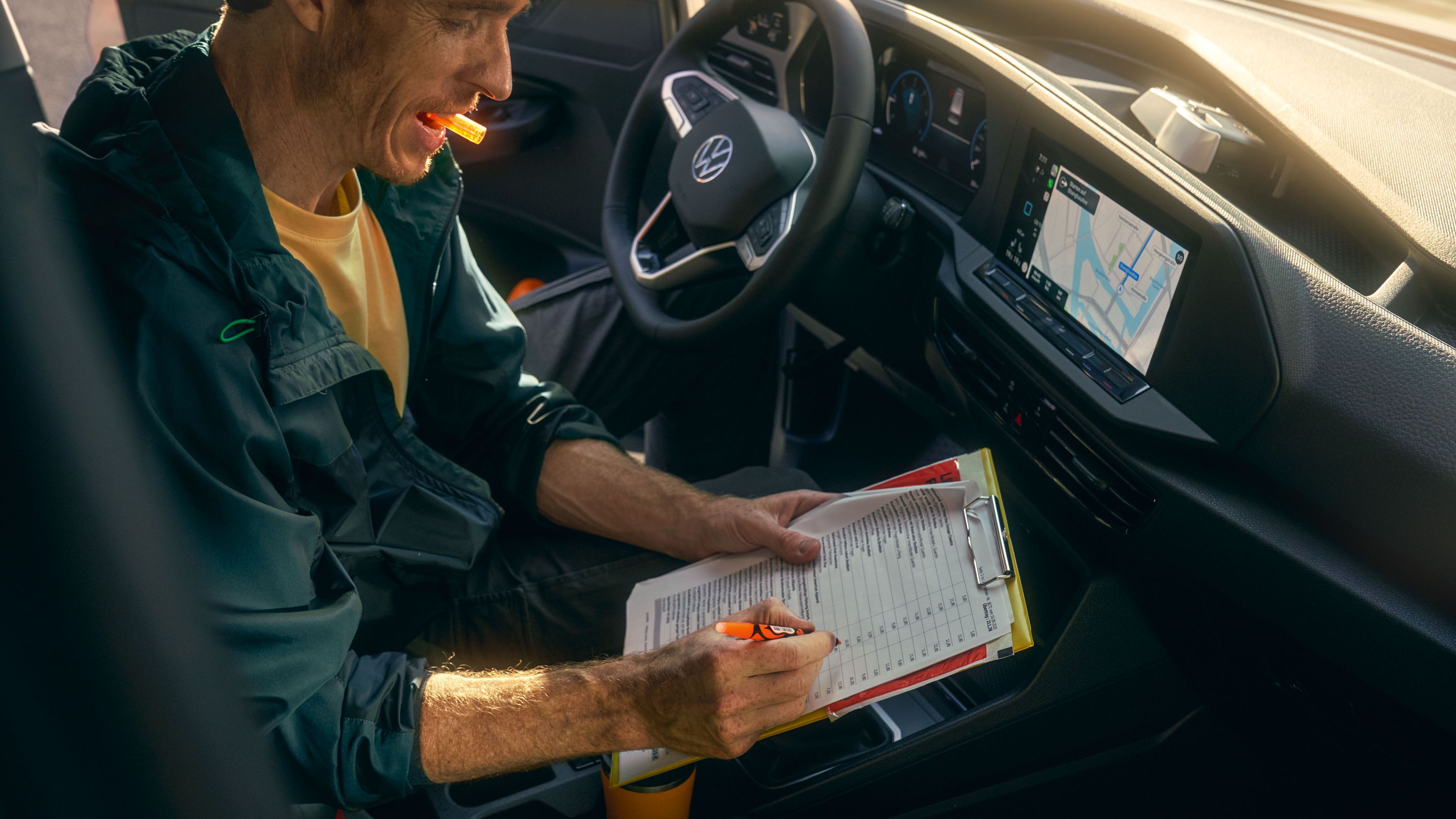 Ein Mann sitzt in einem VW Caddy Cargo und schreibt auf einem Klemmbrett.