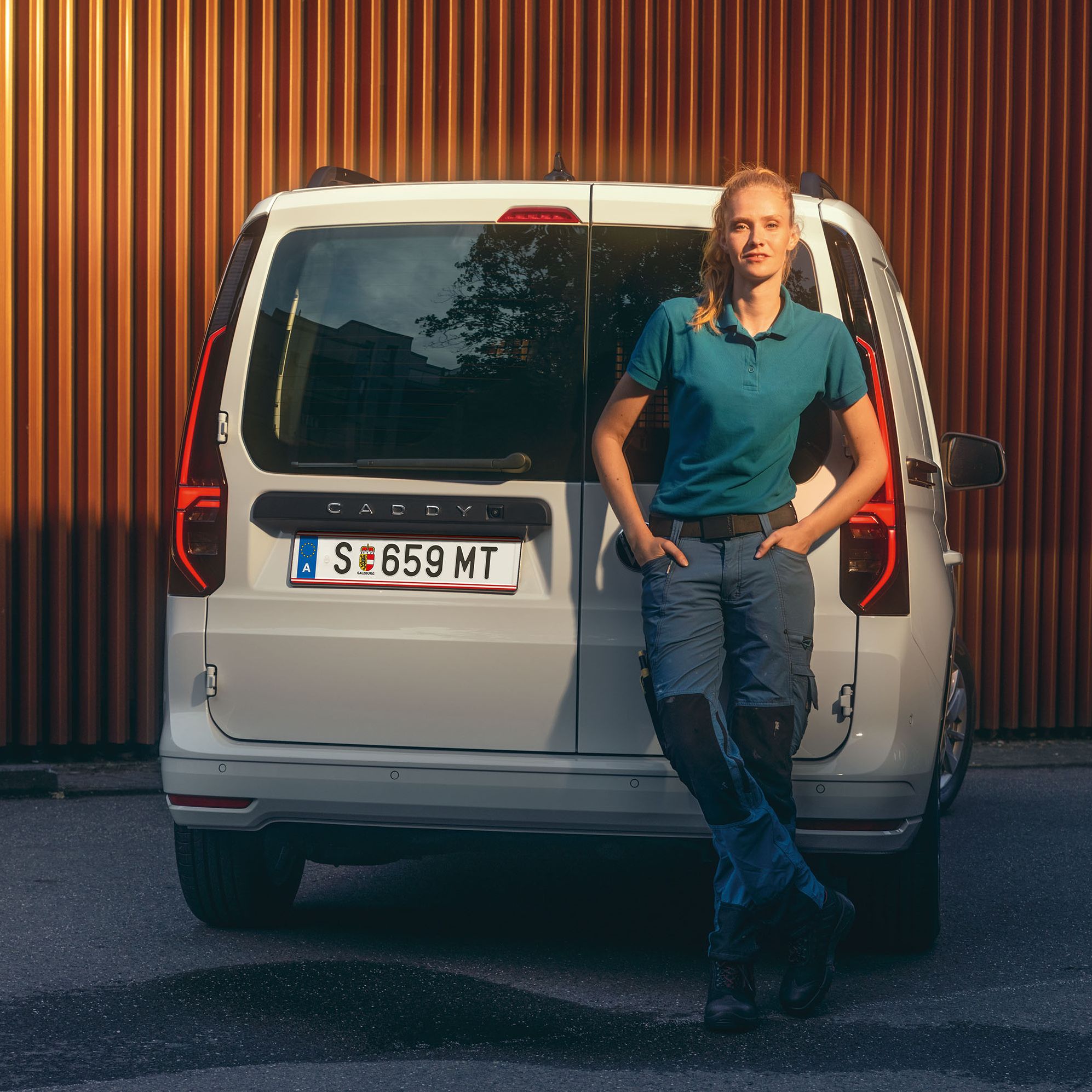 Frau lehnt an Heckklappe eines grauen VW Caddys