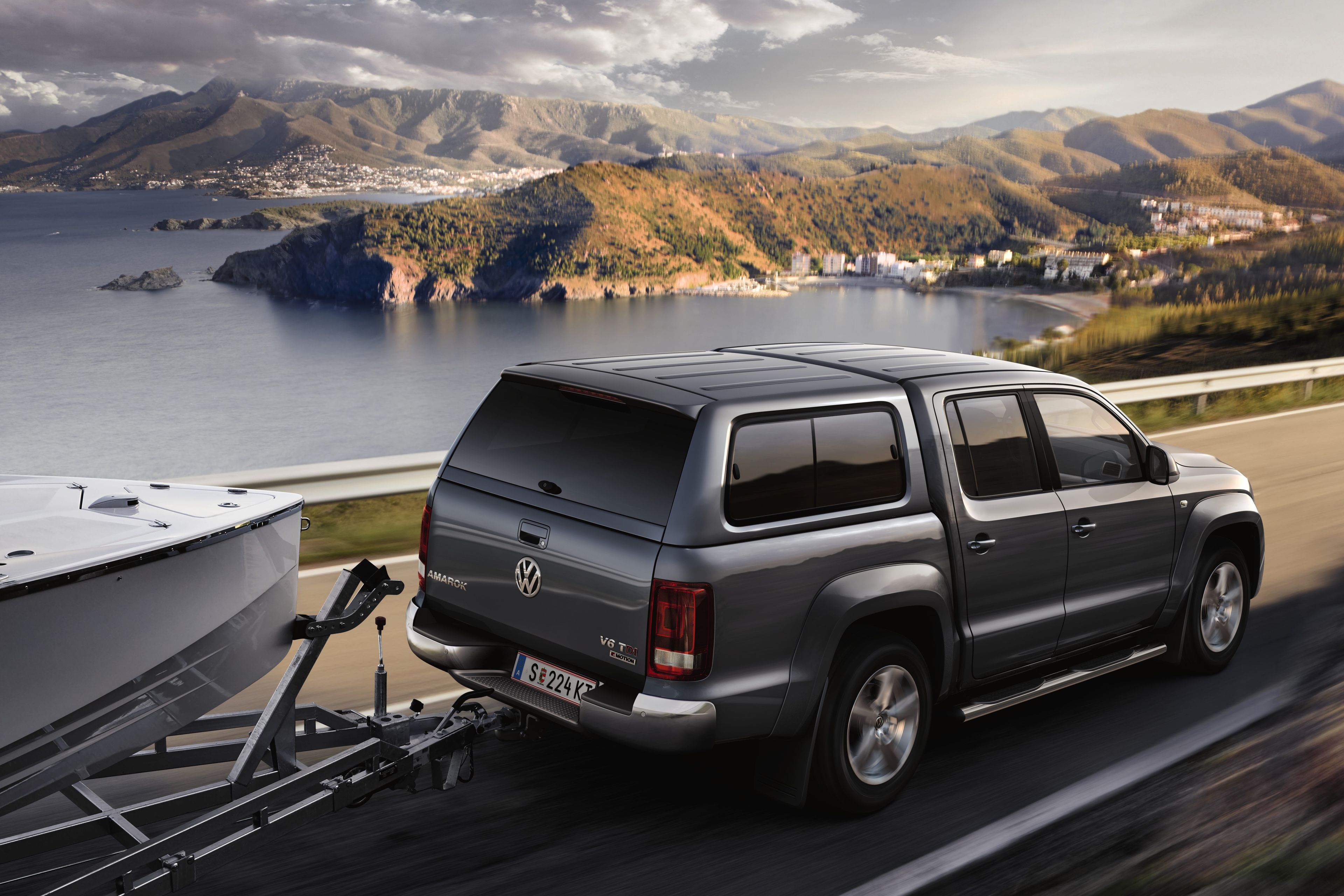 VW Amarok fährt an einer Landstraße um einen See, zieht ein Boot