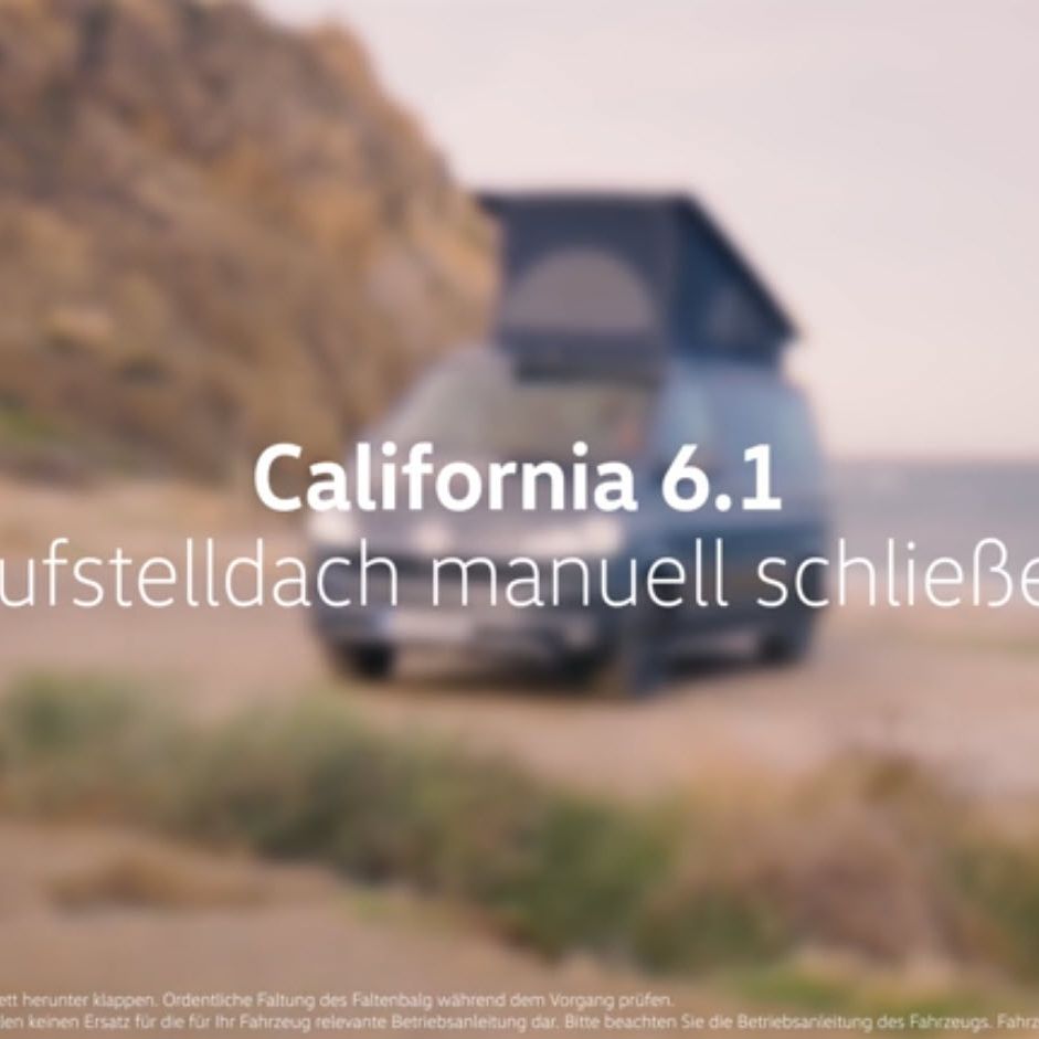 Grauer VW California mit ausgefahrenem Aufstelldach, parkt am Strand