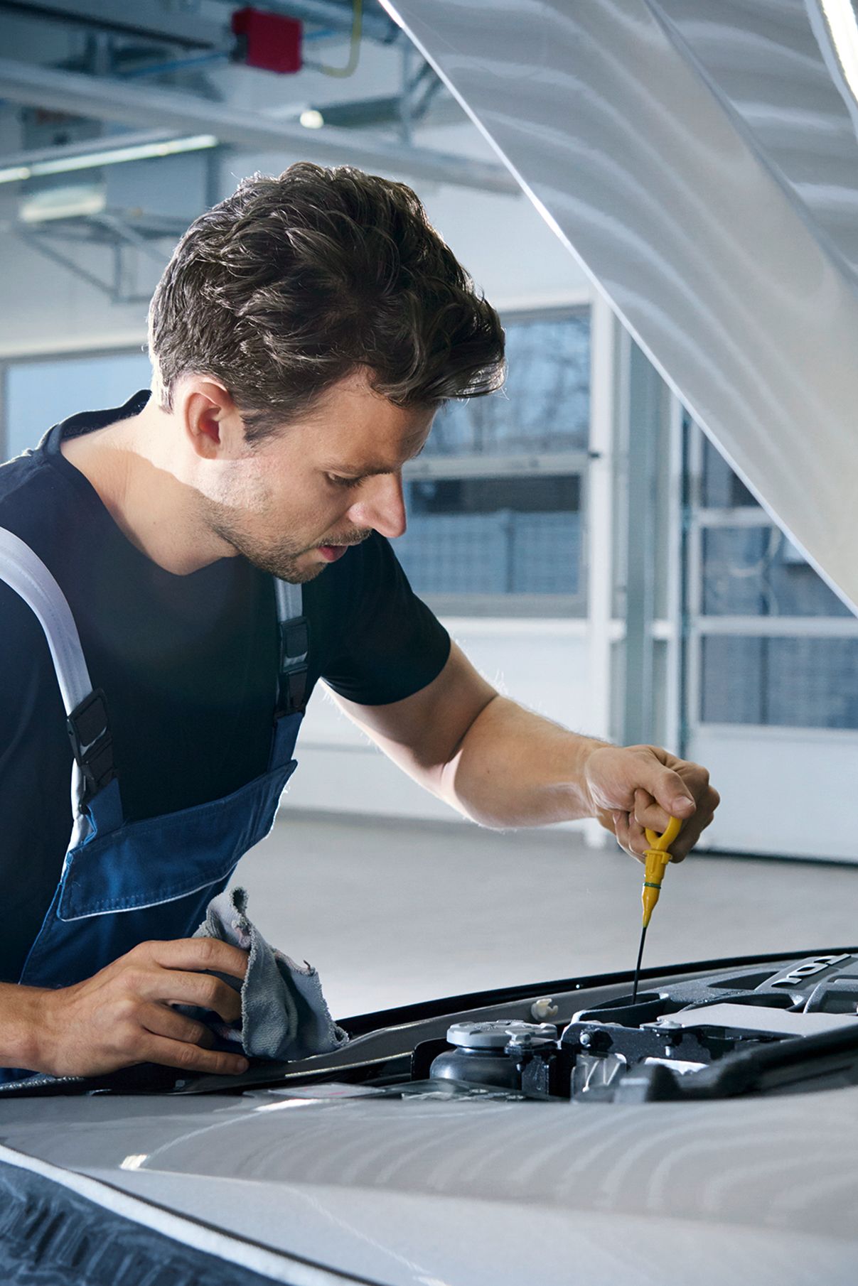 Ein Volkswagen Techniker beim Messen des Ölstandes