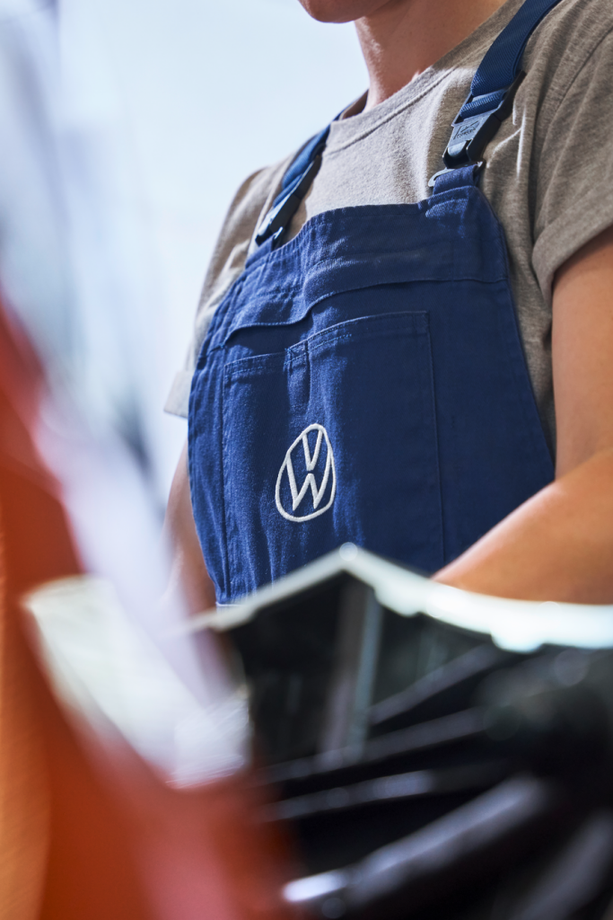 Fokusansicht des Volkswagen Logos der Arbeitskleidung einer Volkswagen Technikerin