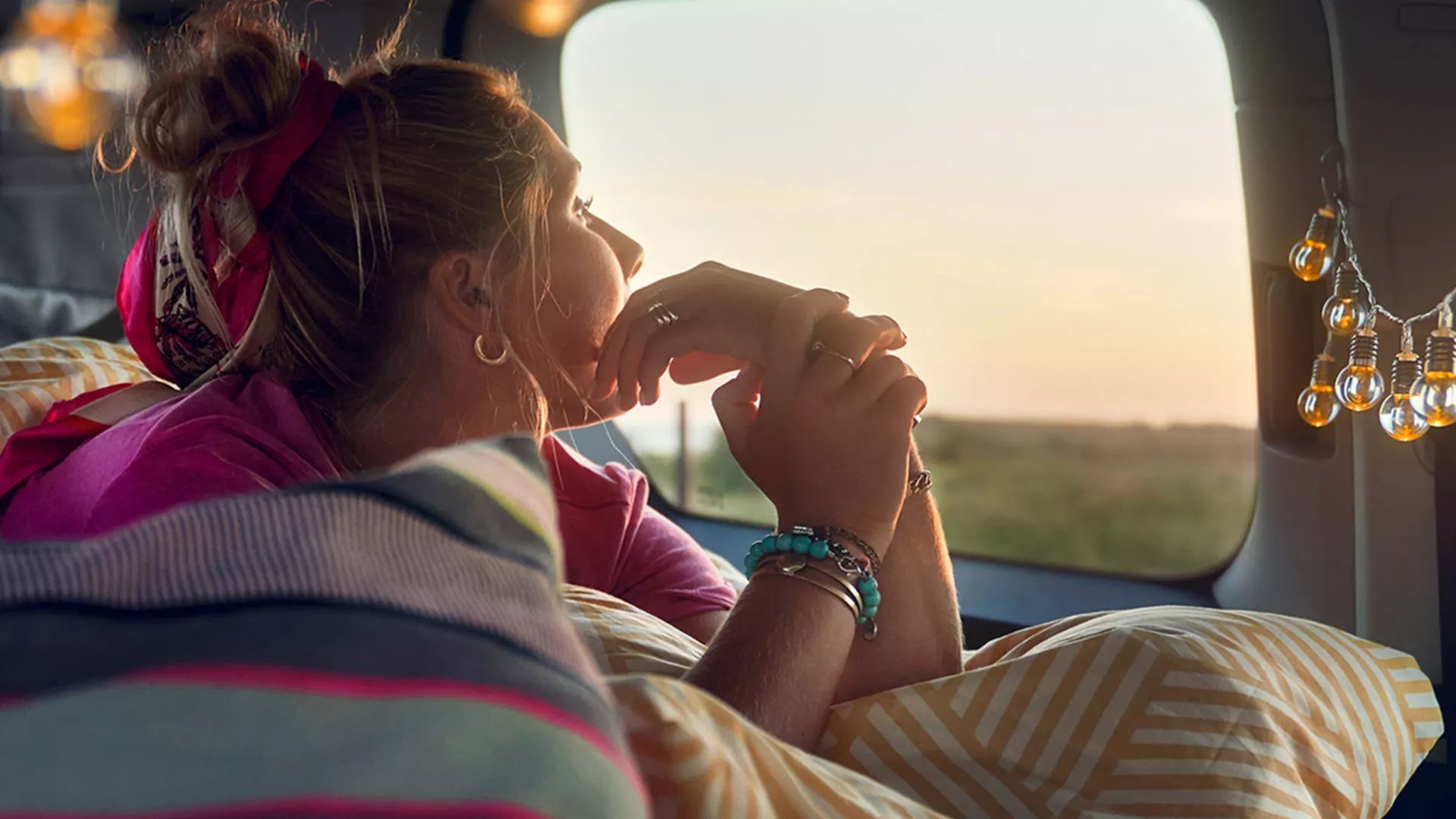 Ein Mädchen liegt auf der Liegefläche eines VW Caddys und schaut aus dem Fenster