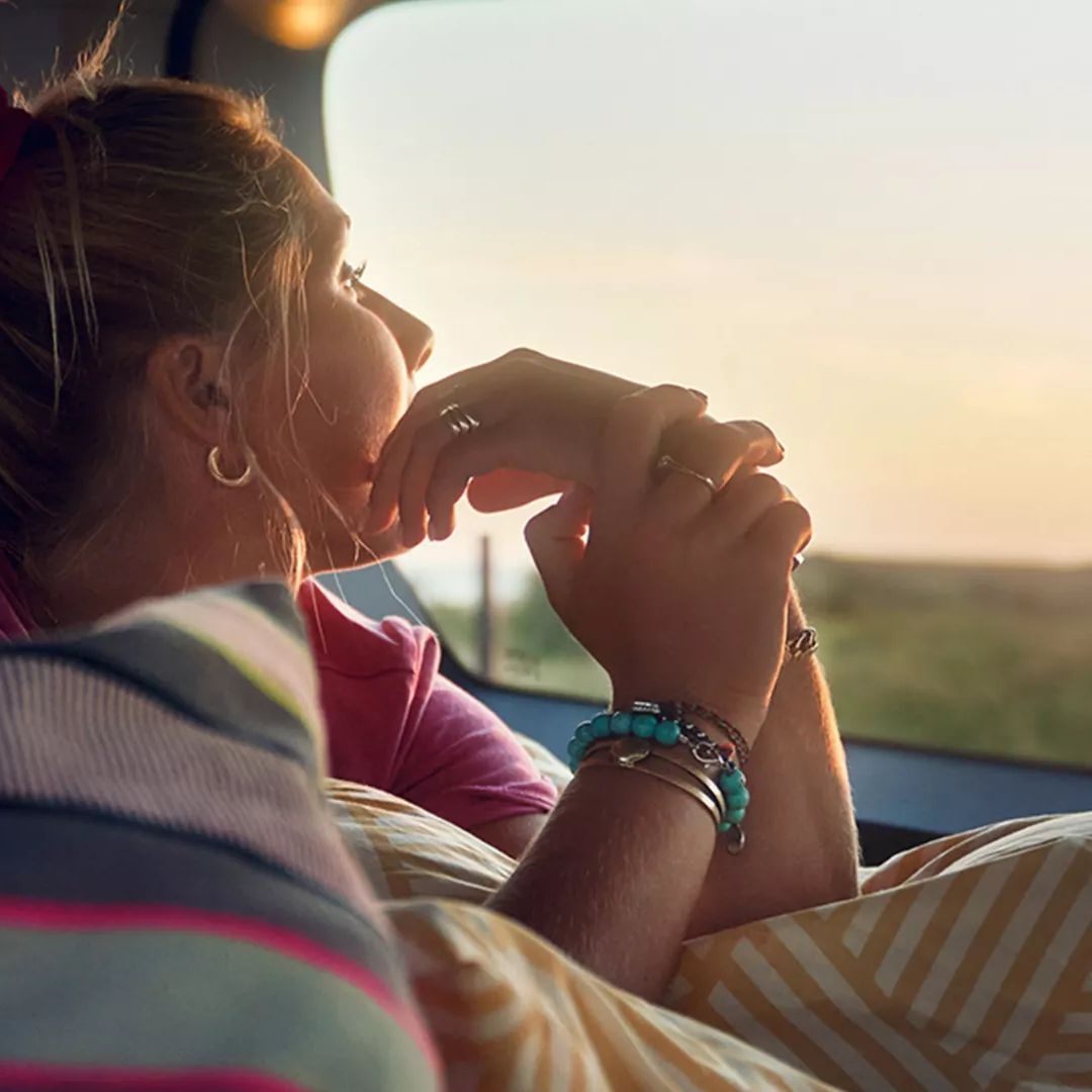 Ein Mädchen liegt auf der Liegefläche eines VW Caddys und schaut aus dem Fenster