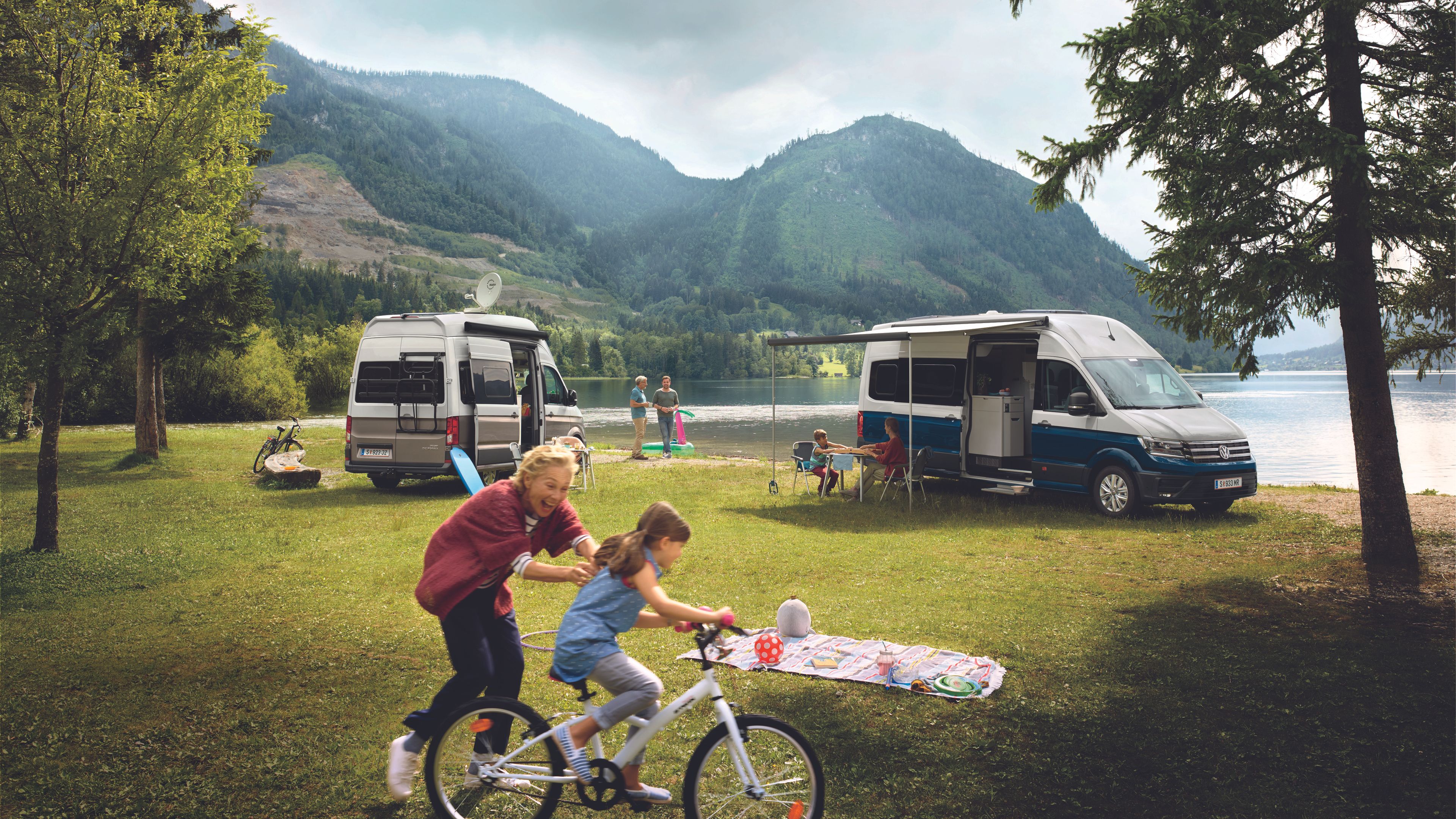 Zwei VW Nutzfahrzeuge stehen auf einem Campingplatz