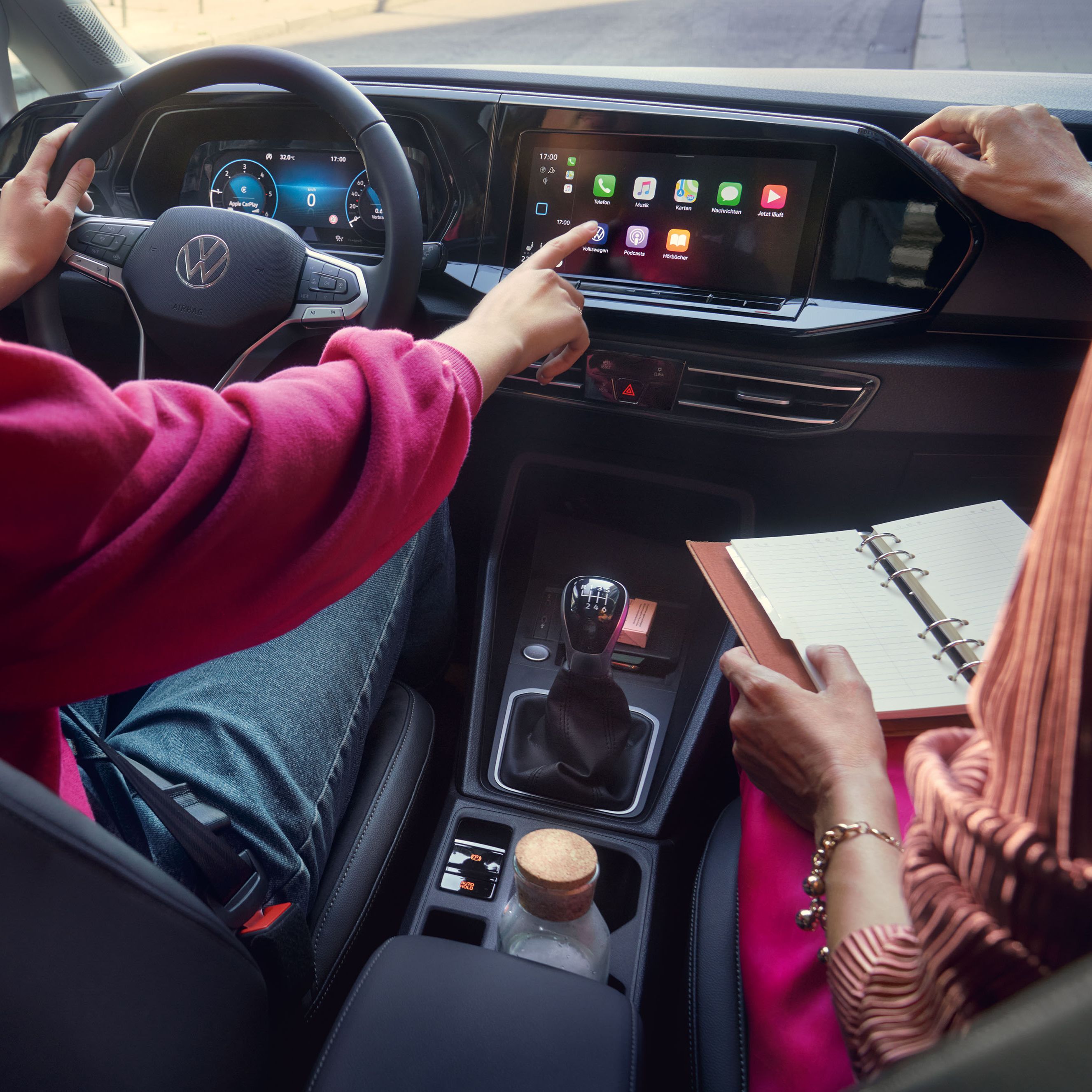 Frau sitzt im VW Caddy California und bedient das Display. 