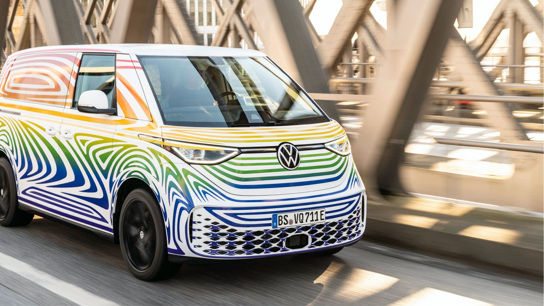 VW ID. Buzz im bunten Camouflage fährt auf der Straße