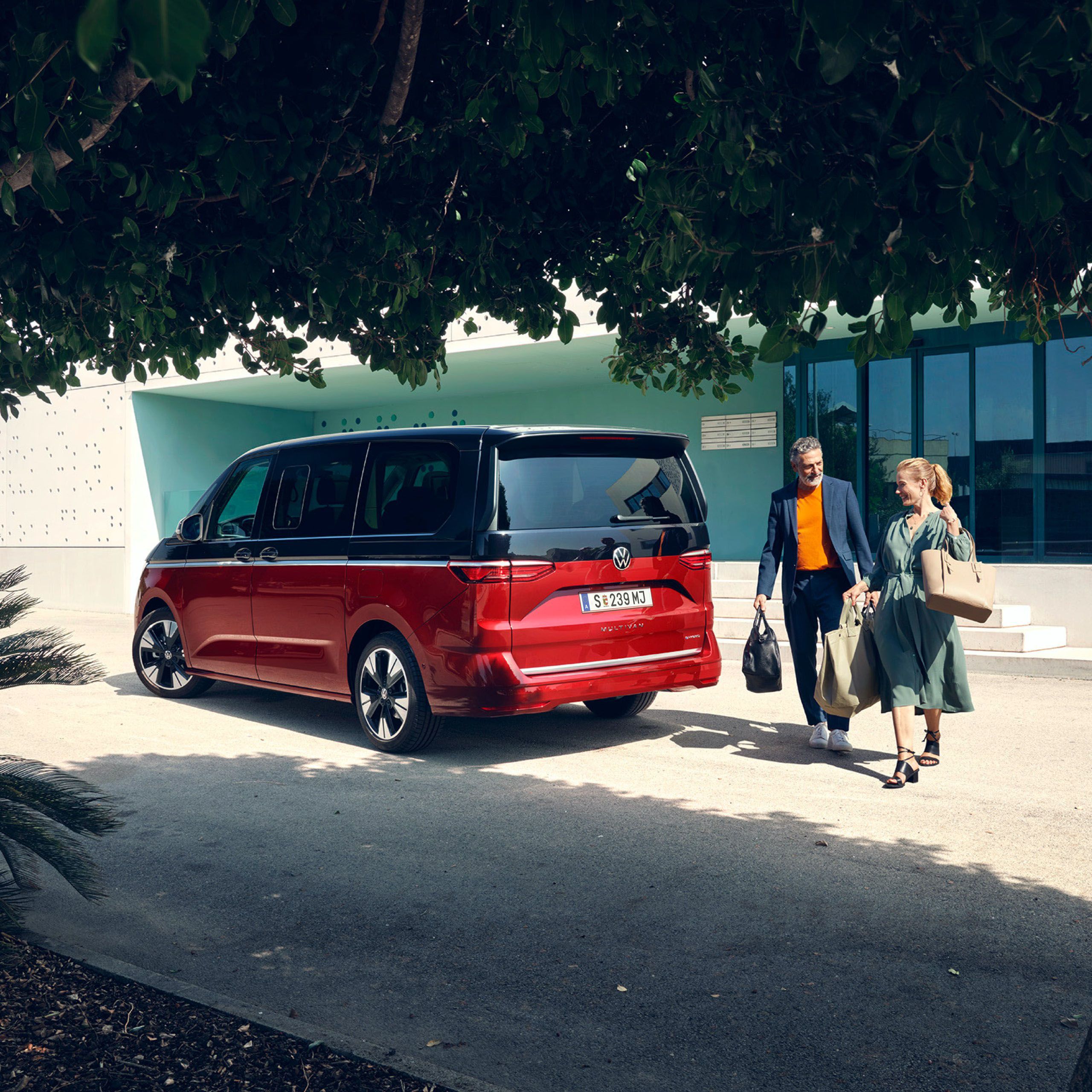 Heck des neuen VW T7 Multivan Style ist zu sehen und ein Mann und eine Frau spazieren vorbei