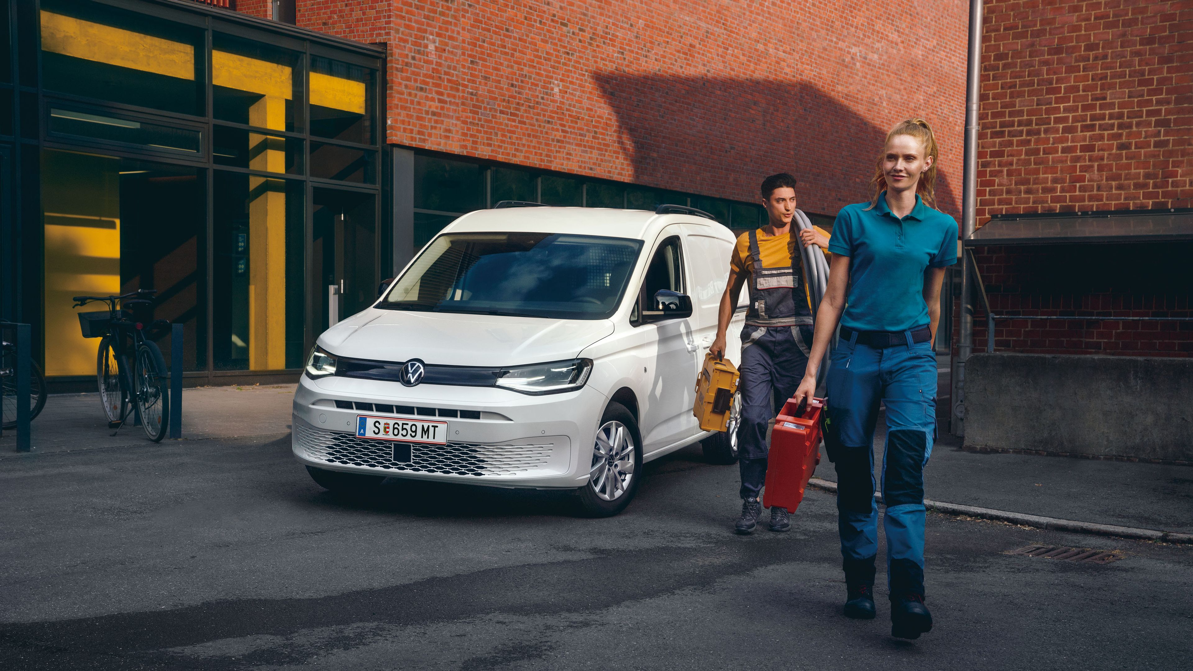 Ein Handwerker-Team vor einem weißen VW Caddy Cargo.