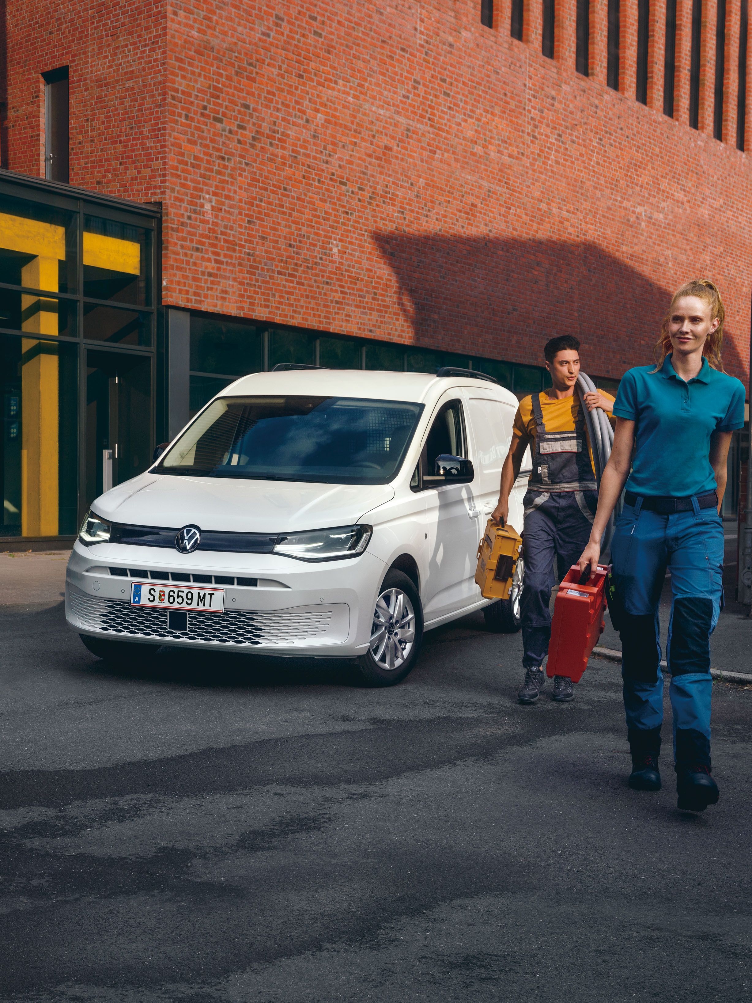 Ein Handwerker-Team vor einem weißen VW Caddy Cargo.