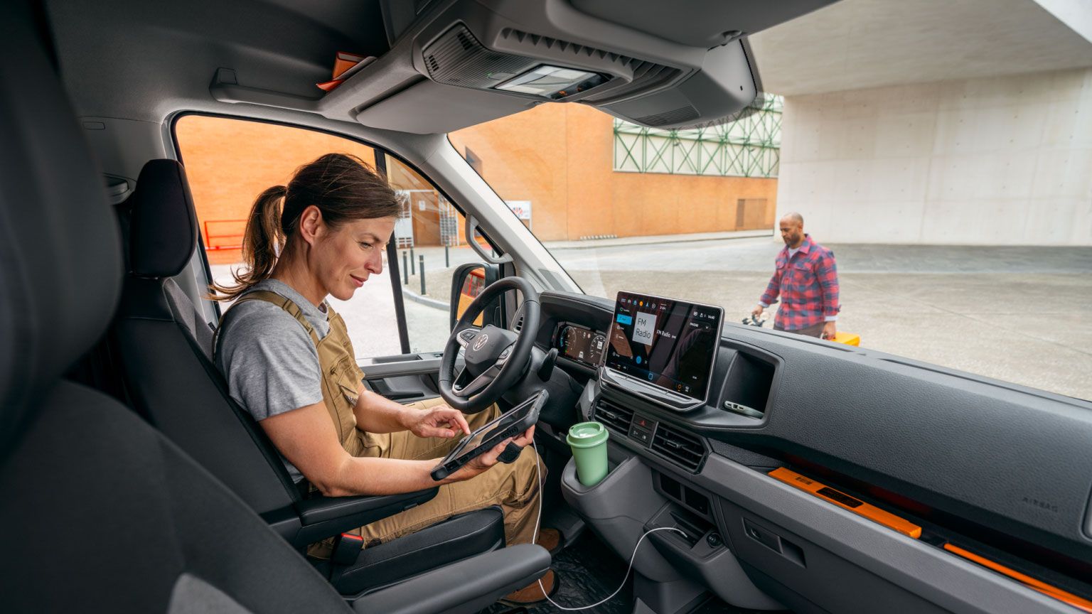 Eine Volkswagen Technikerin sitzt mit einem Tablet im Cockpit eines VW-Nutzfahrzeugs