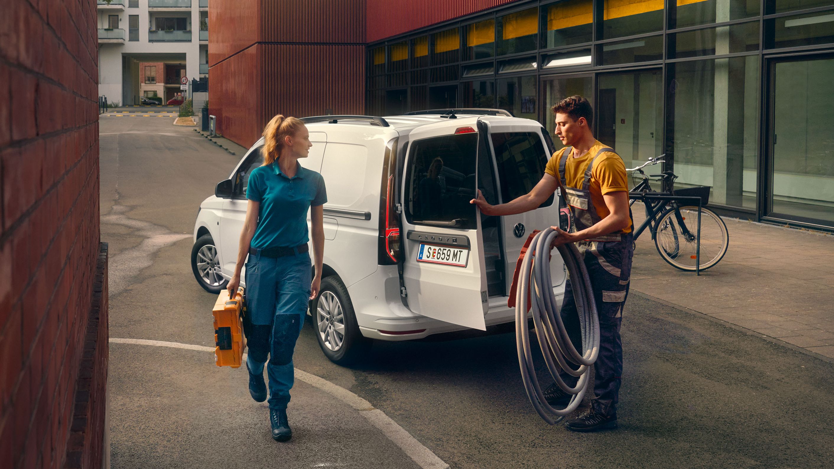 Handwerker Team räumt einen weißen Caddy Cargo aus.