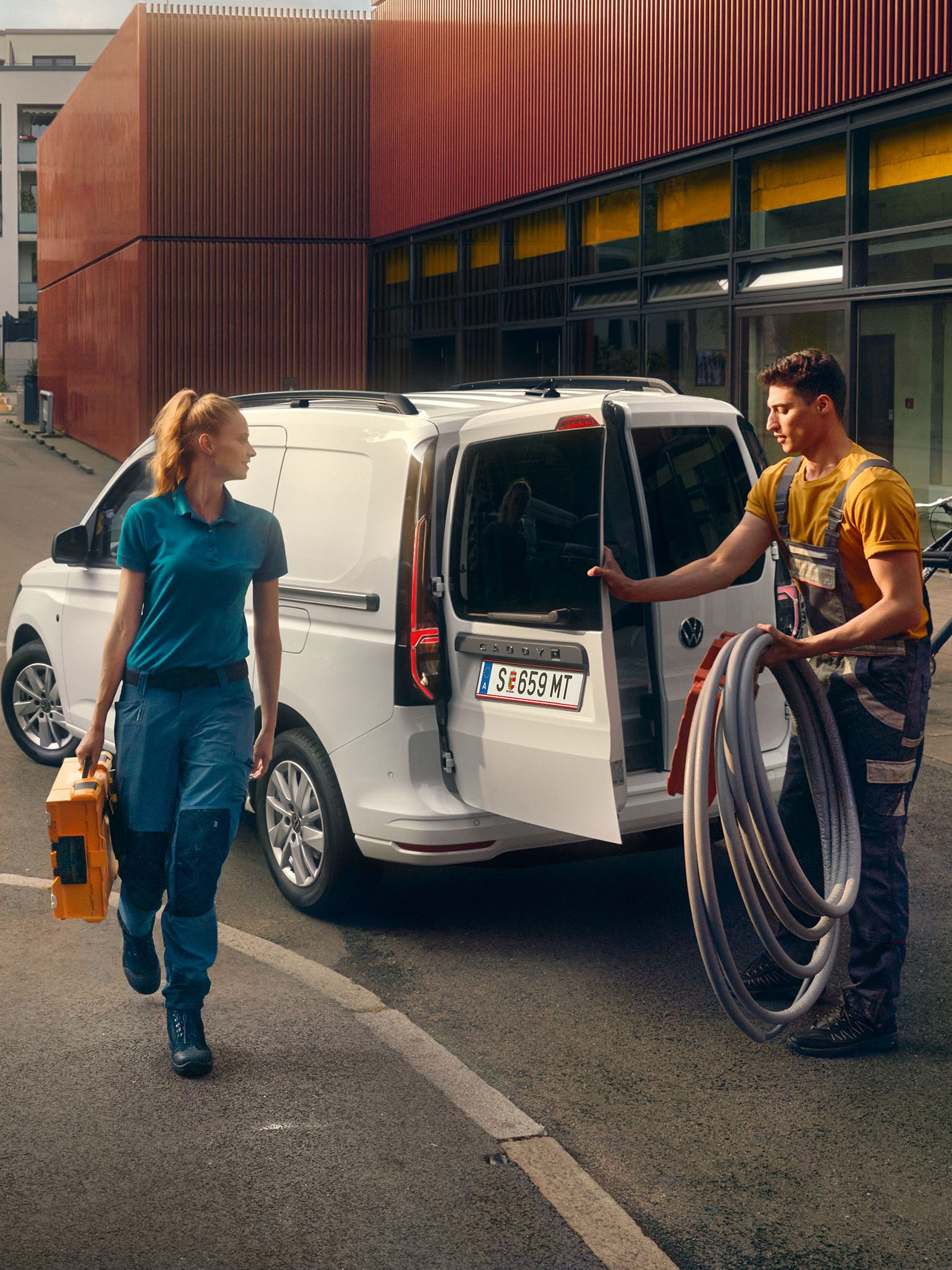 Handwerker Team räumt einen weißen Caddy Cargo aus.