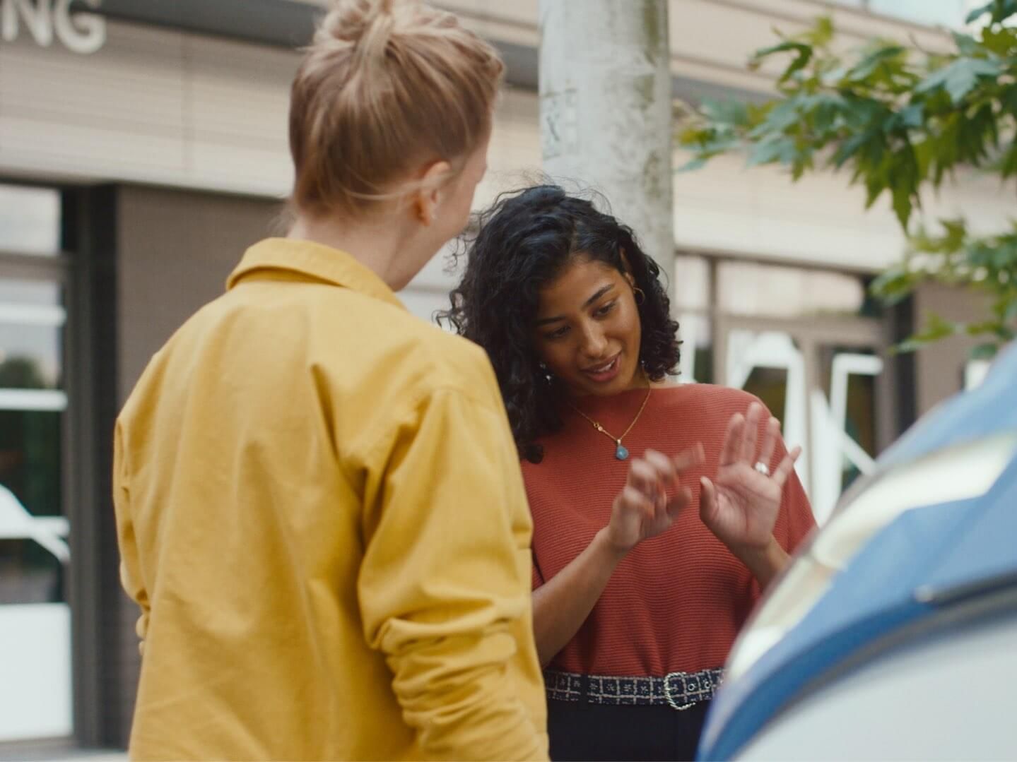 Zwei Frauen unterhalten sich neben VW ID. Buzz