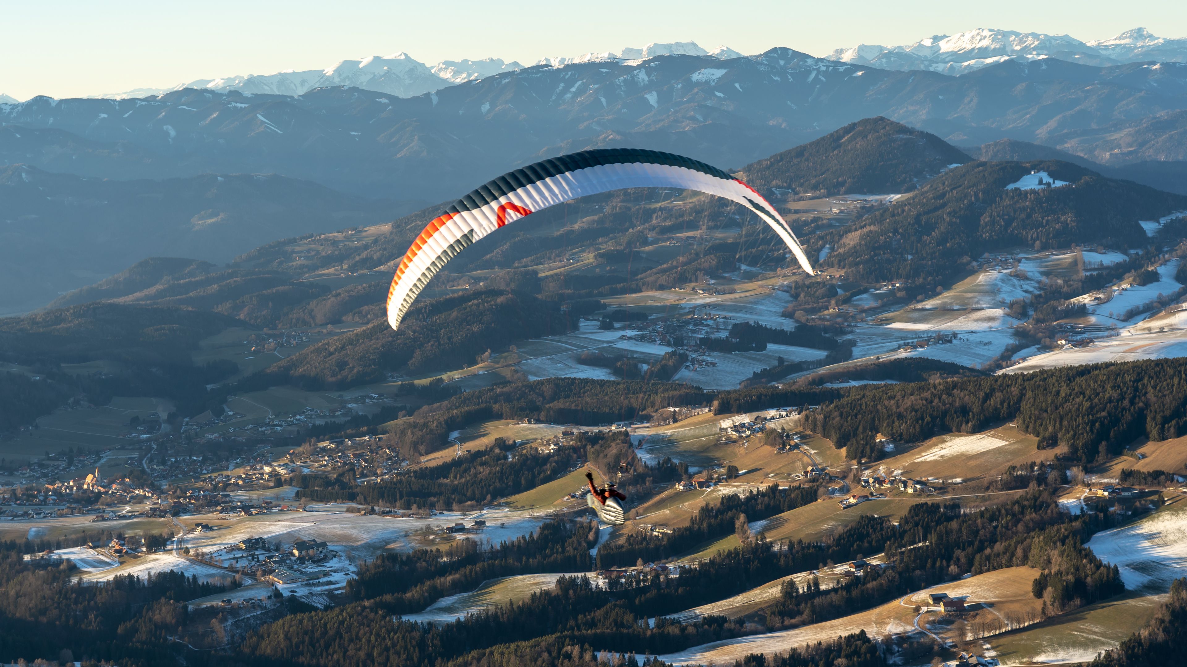 Thomas Friedrich beim Paragleiten über einem kleinen Dorf in den Bergen