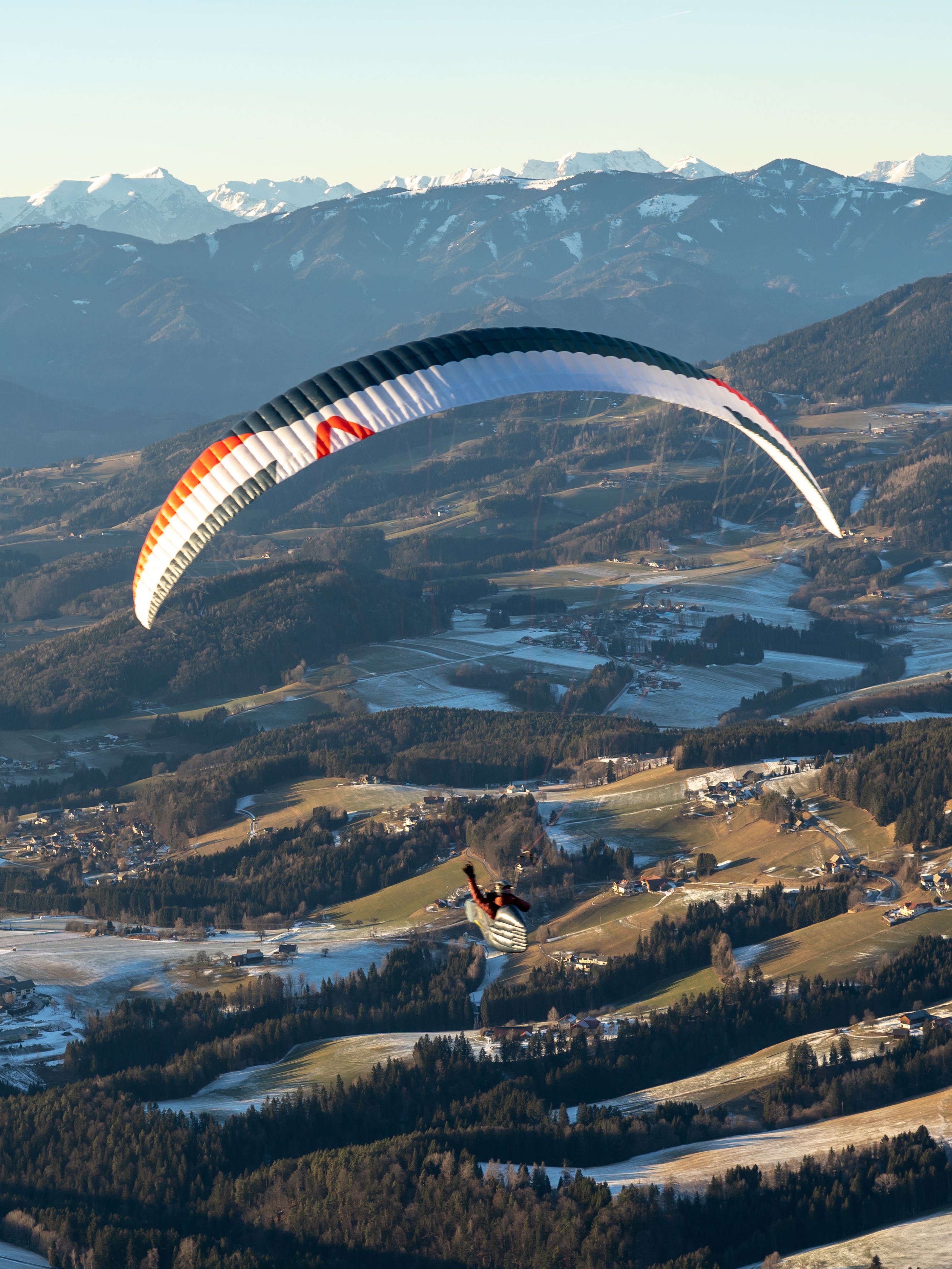 Thomas Friedrich beim Paragleiten über einem kleinen Dorf in den Bergen